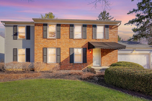 colonial inspired home with a garage and brick siding