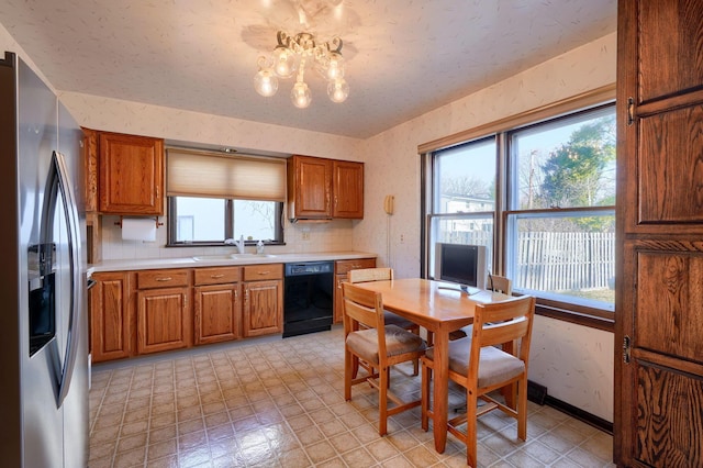 kitchen featuring wallpapered walls, a sink, stainless steel fridge, dishwasher, and brown cabinets