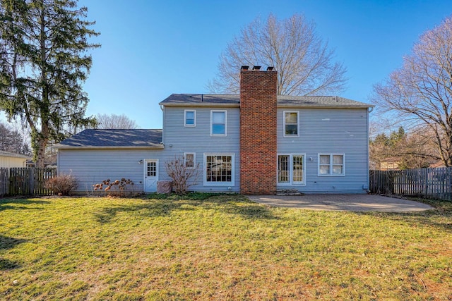 back of house featuring a patio, a yard, a fenced backyard, and a chimney