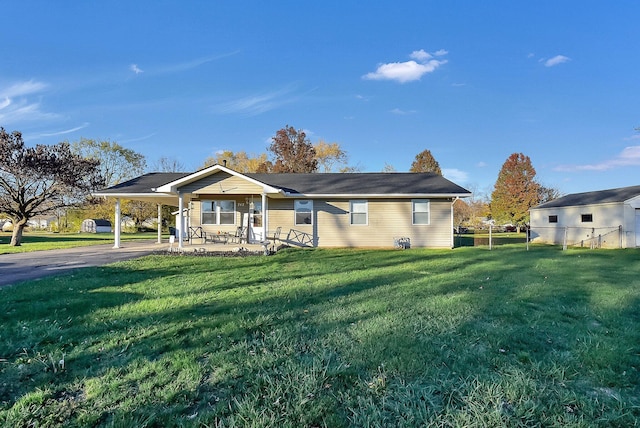 view of front facade featuring a front lawn, a carport, fence, and driveway