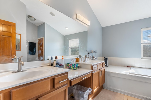 bathroom featuring vanity, vaulted ceiling, plenty of natural light, and visible vents