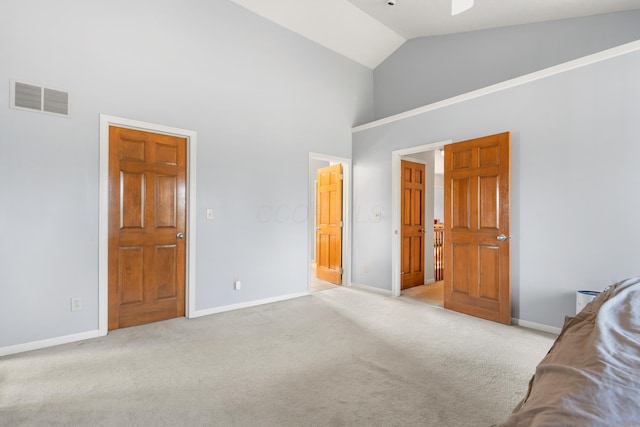 unfurnished bedroom featuring high vaulted ceiling, light colored carpet, visible vents, and baseboards