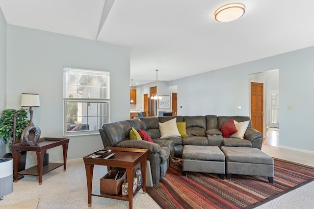 living area with an inviting chandelier, light colored carpet, and baseboards