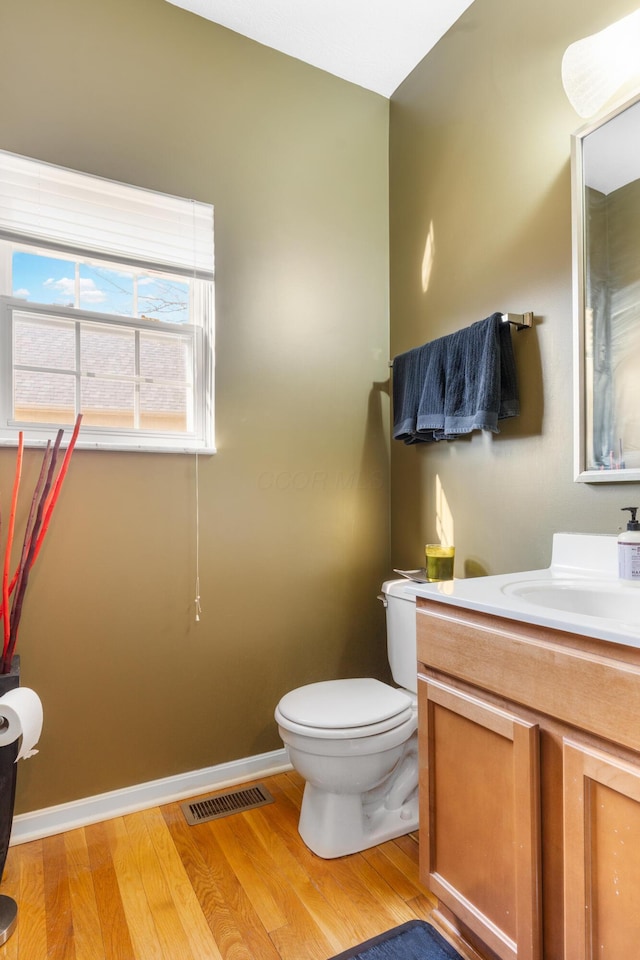 half bathroom featuring visible vents, toilet, baseboards, and wood finished floors