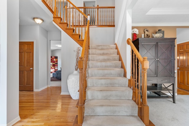 staircase with crown molding, baseboards, and wood finished floors