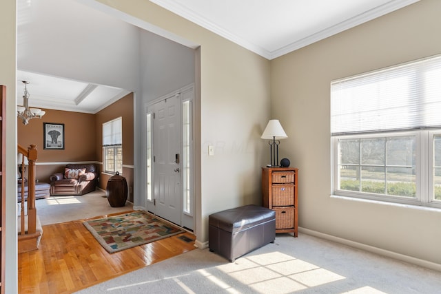 carpeted entryway with baseboards, crown molding, and an inviting chandelier