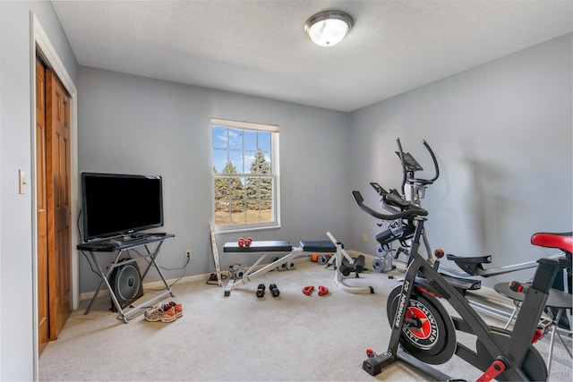 exercise area featuring baseboards, carpet floors, and a textured ceiling