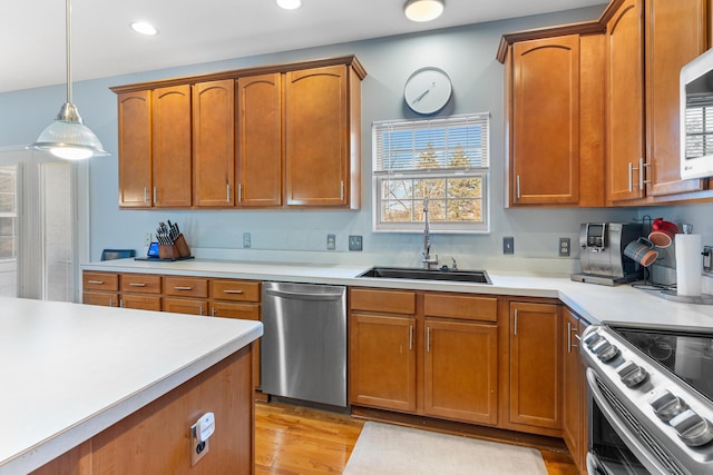 kitchen featuring a sink, stainless steel appliances, hanging light fixtures, and light countertops