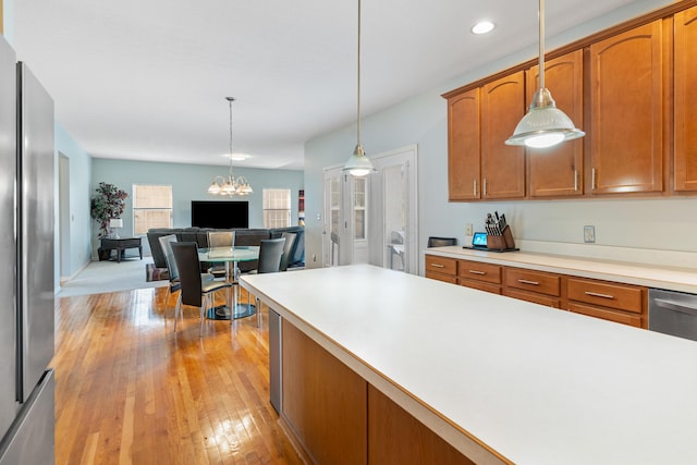 kitchen with light wood finished floors, a chandelier, light countertops, freestanding refrigerator, and hanging light fixtures