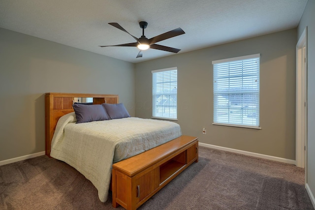 bedroom with dark colored carpet, baseboards, and a textured ceiling