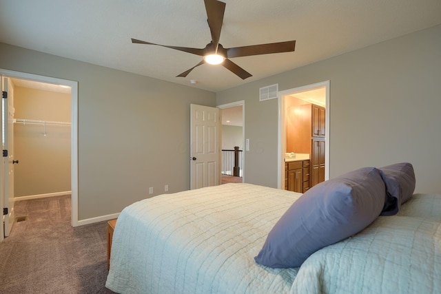 carpeted bedroom featuring a ceiling fan, baseboards, visible vents, a spacious closet, and ensuite bathroom