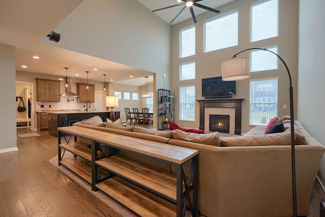 living room with a ceiling fan, recessed lighting, wood-type flooring, and a tile fireplace