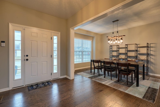 entryway with a notable chandelier, baseboards, dark wood-type flooring, and a textured ceiling