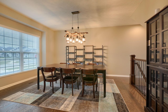 dining room with dark wood finished floors, a chandelier, and baseboards