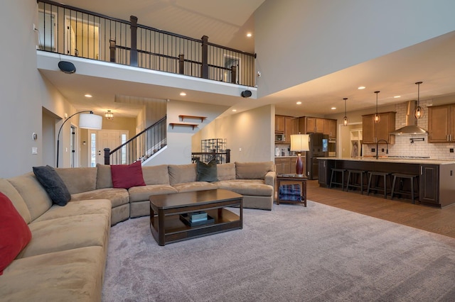 carpeted living area featuring recessed lighting, wood finished floors, and stairs