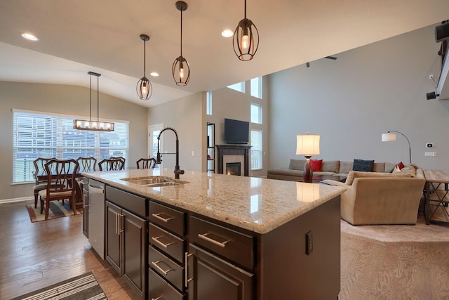 kitchen featuring dark brown cabinets, dishwasher, lofted ceiling, light wood-style floors, and a sink