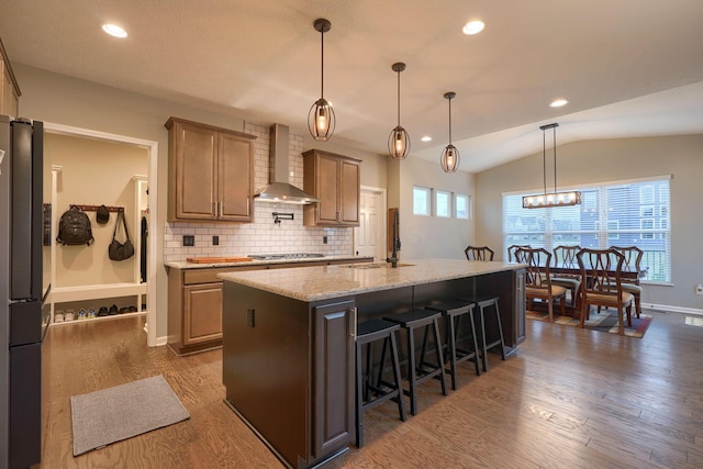 kitchen featuring a sink, dark wood-style floors, wall chimney exhaust hood, lofted ceiling, and stainless steel gas cooktop