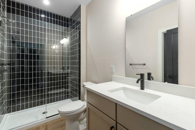 full bathroom with a tile shower, toilet, and vanity