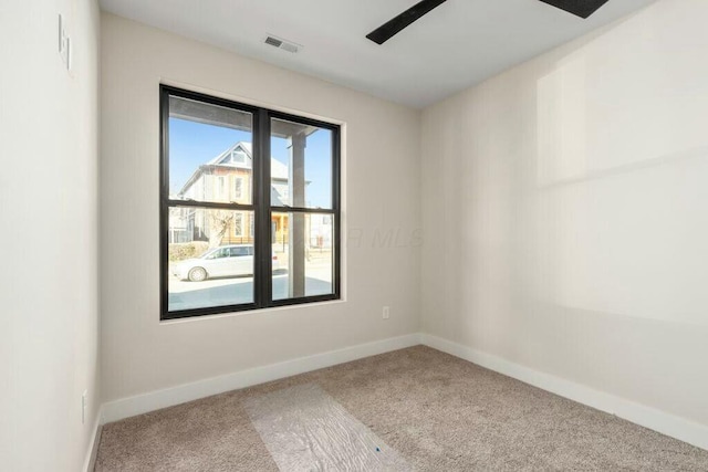 carpeted spare room with visible vents, ceiling fan, and baseboards