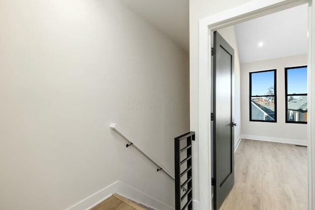 interior space with lofted ceiling, light wood-style flooring, an upstairs landing, and baseboards