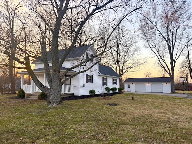 view of front facade with driveway, a detached garage, a porch, an outdoor structure, and a front yard