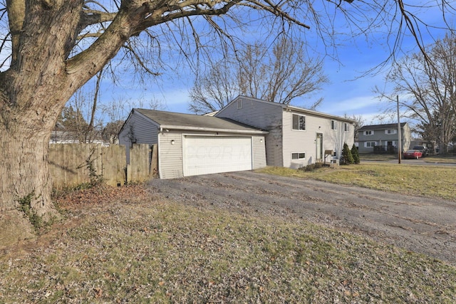 view of side of home featuring fence, a garage, and driveway