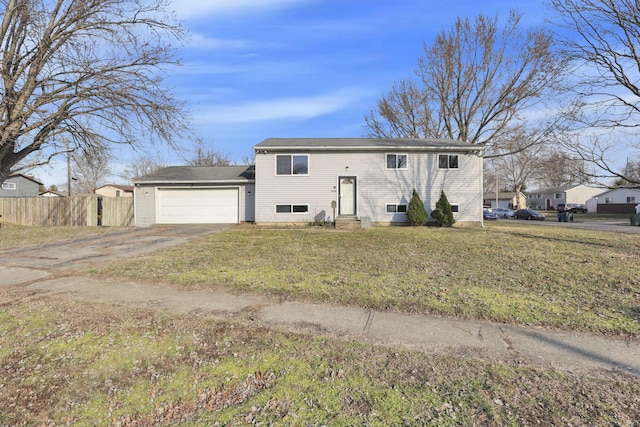 split foyer home featuring a front yard, fence, driveway, an attached garage, and entry steps