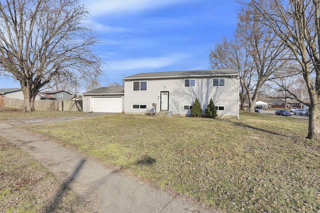 split foyer home featuring a front lawn, entry steps, driveway, fence, and an attached garage