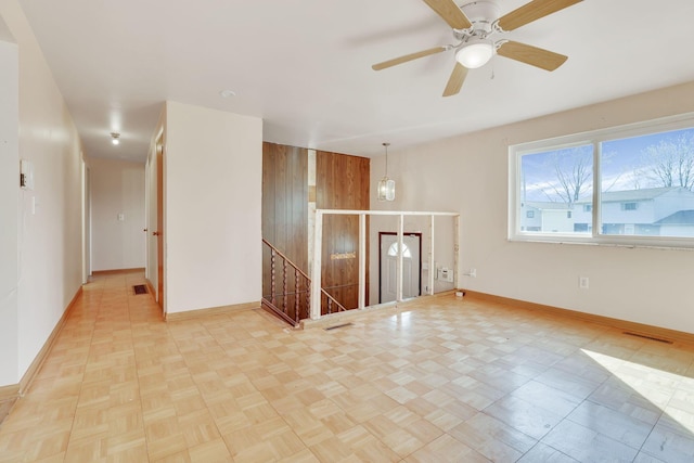 empty room featuring visible vents, baseboards, and wood walls