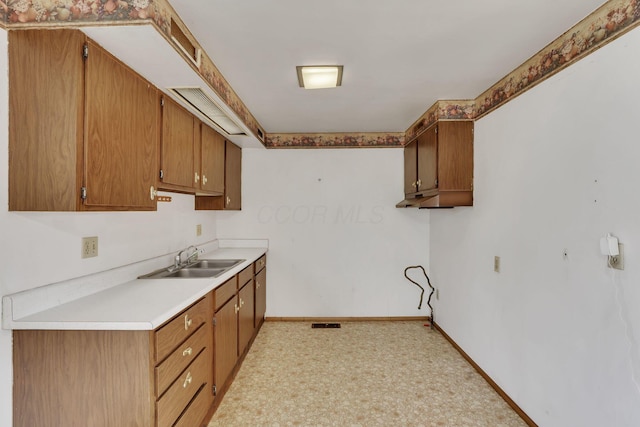 kitchen featuring light countertops, visible vents, baseboards, and a sink