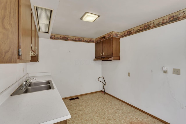 interior space featuring a sink, visible vents, baseboards, and light countertops