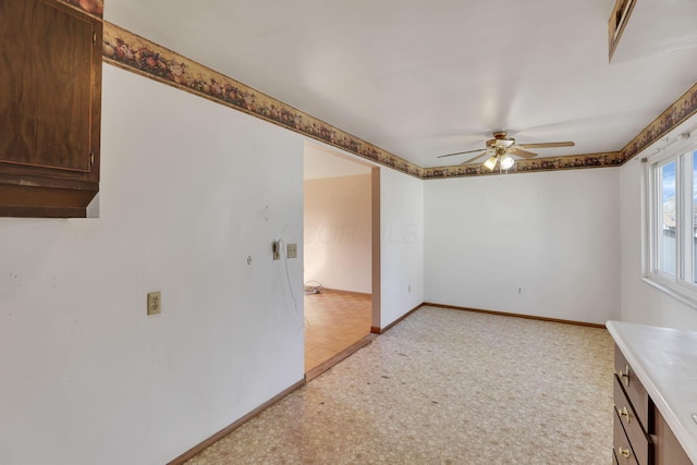 unfurnished room with ceiling fan and baseboards