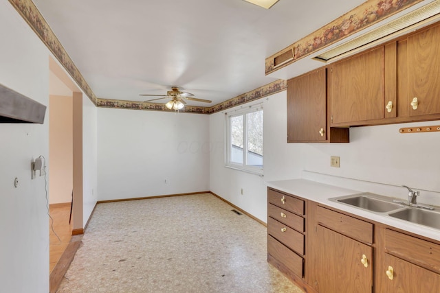 kitchen with visible vents, ceiling fan, baseboards, light countertops, and a sink