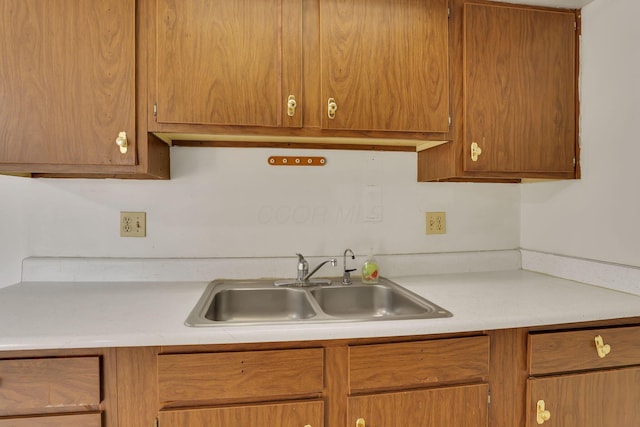 kitchen featuring brown cabinetry, light countertops, and a sink