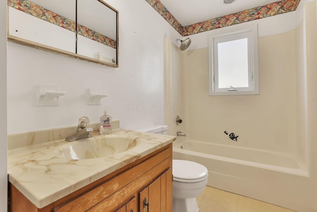 bathroom with toilet, vanity, and  shower combination