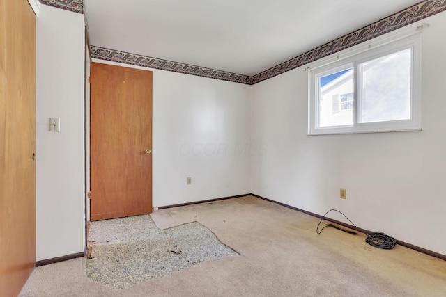 carpeted spare room featuring baseboards