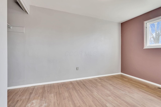 spare room featuring baseboards and light wood finished floors