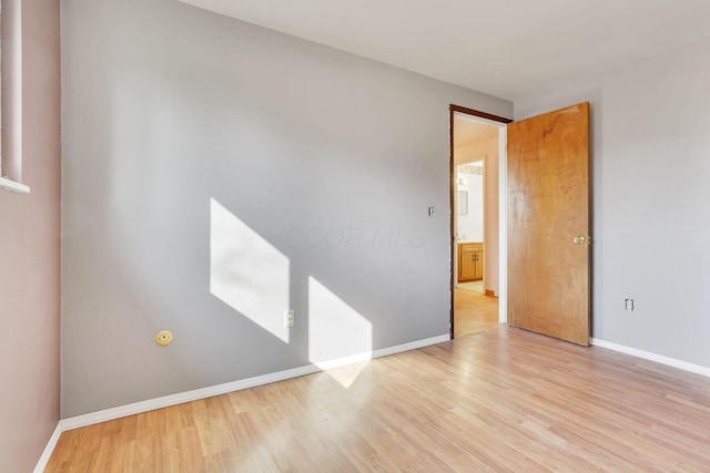 spare room featuring baseboards and light wood finished floors