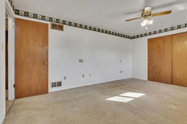 unfurnished bedroom with a closet, a ceiling fan, visible vents, and carpet floors