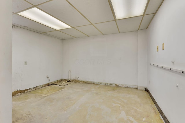 unfurnished room with unfinished concrete flooring and a paneled ceiling