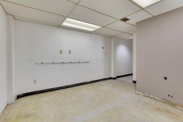 empty room featuring baseboards, a paneled ceiling, and concrete flooring