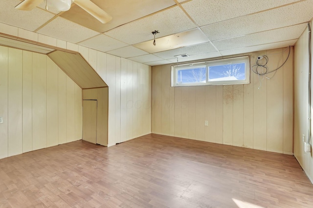 interior space with a drop ceiling, wood finished floors, and a ceiling fan