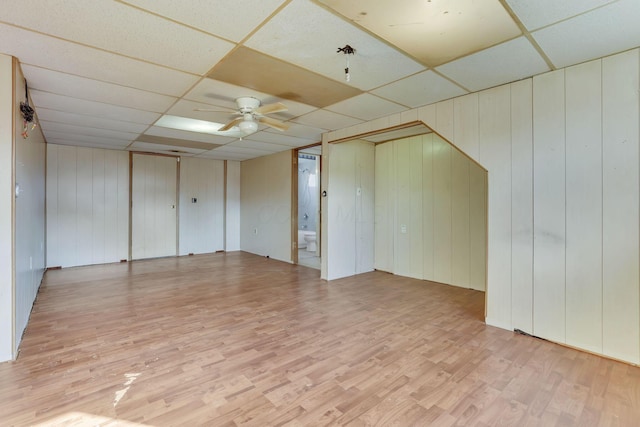 unfurnished room featuring a drop ceiling, light wood-style floors, and ceiling fan