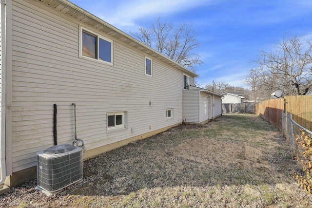 back of house featuring central AC unit, a lawn, and a fenced backyard