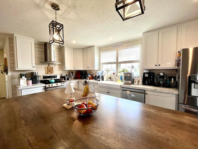 kitchen featuring a sink, stainless steel appliances, wall chimney exhaust hood, and white cabinetry