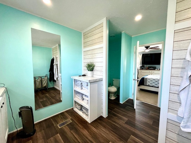 hallway with dark wood finished floors, visible vents, and a textured ceiling