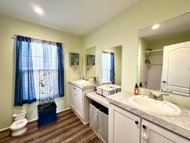 bathroom featuring walk in shower, two vanities, wood finished floors, and a sink