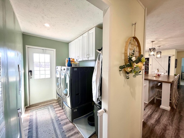 laundry room featuring cabinet space, separate washer and dryer, wood finished floors, and a textured ceiling