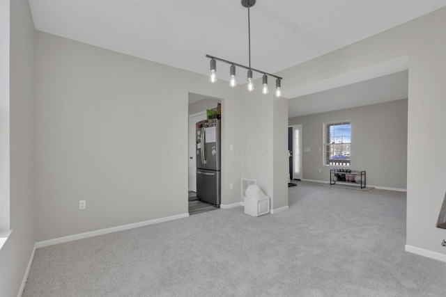 carpeted spare room featuring visible vents, track lighting, and baseboards