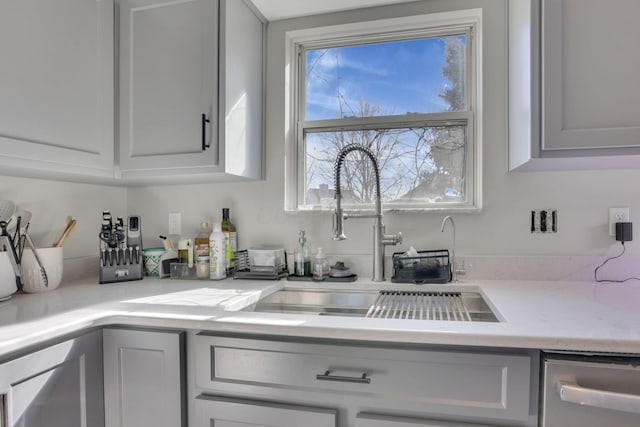 kitchen with stainless steel dishwasher, light countertops, and a sink